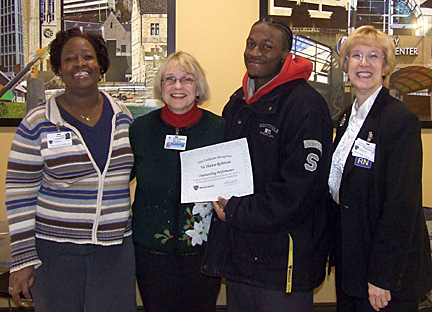 Va’Shawn Robinson held a certificate he received for his heroic actions and posed for a photo with, from left, Arlene Fell, director of environmental services, Susan Arbaugh and Norma Tomlinson, associate vice president and associate executive director for UT Medical Center.
