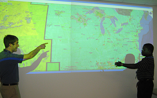 Jeffrey Kodysh and his mentor, Dr. Olufemi Omitaomu, look at the real-time visualization tool developed at Oak Ridge National Laboratory for monitoring the U.S. electric grid transmission system.