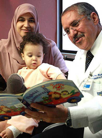 Dr. Azedine Medhkour read to Ayoub, who was held by his mother, Dalila Hamdi, who traveled from Algeria last year so her son could receive free surgical treatment in Toledo. Medhkour and UT Medical Center surgeons corrected Ayoub’s spinal cord defect.