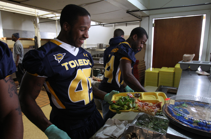 Isaiah Ballard, junior defensive back, and his teammates dish out lunch with the Little Caesars Love Kitchen.