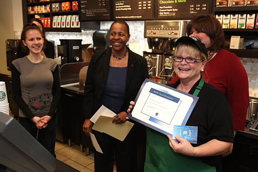 Annette Gernheuser, a cashier at Starbucks, showed off the Wow Award she received last week. She was surprised with the honor by, from left, Leah Mullen, Dr. Kaye Patten Wallace and Michelle Martinez.