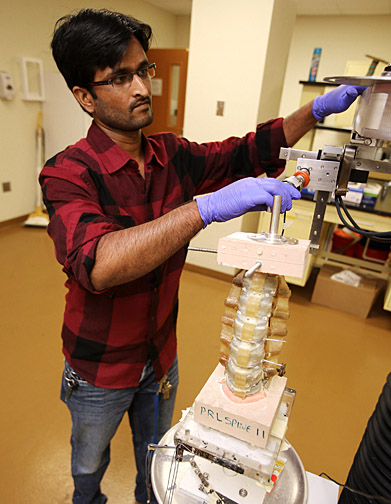 Manoj Kodigudla, research engineer in Dr. Vijay Goel's lab, made adjustments to the spine testing device in the lab.