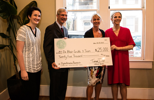 Dr. Blair Grubb received a $25,000 award from the Dysautonomia Advocacy Foundation last week. Posing for a photo with the physician were, from left, Kaylee Sills, acting executive director of the Dysautonomia Advocacy Foundation; Sarah Glenn Smith, president of the Dysautonomia Advocacy Foundation; and Ainsley Glenn, founding director of the Dysautonomia Advocacy Foundation.