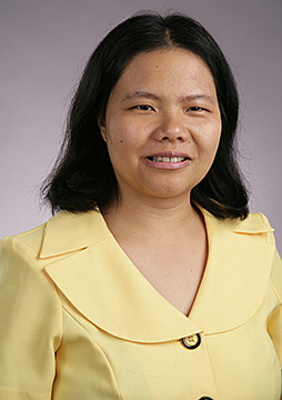 portrait of Enjie Hall; she is wearing a yellow top and is smiling