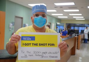 Pierre Maldonado holds a sign that reads "I got the shot for"