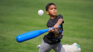 Boy swings blue bat to hit wiffle ball in Carter Field