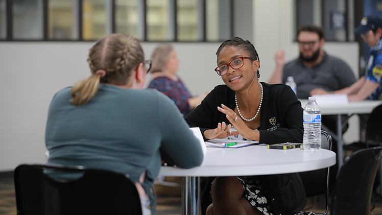 Two women talk at a table as part of a UToledo Human Library event.