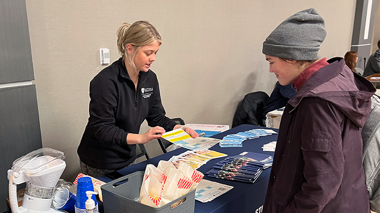 A student meets with a UToledo employee at an indoor Spring Student Involvement Fair.