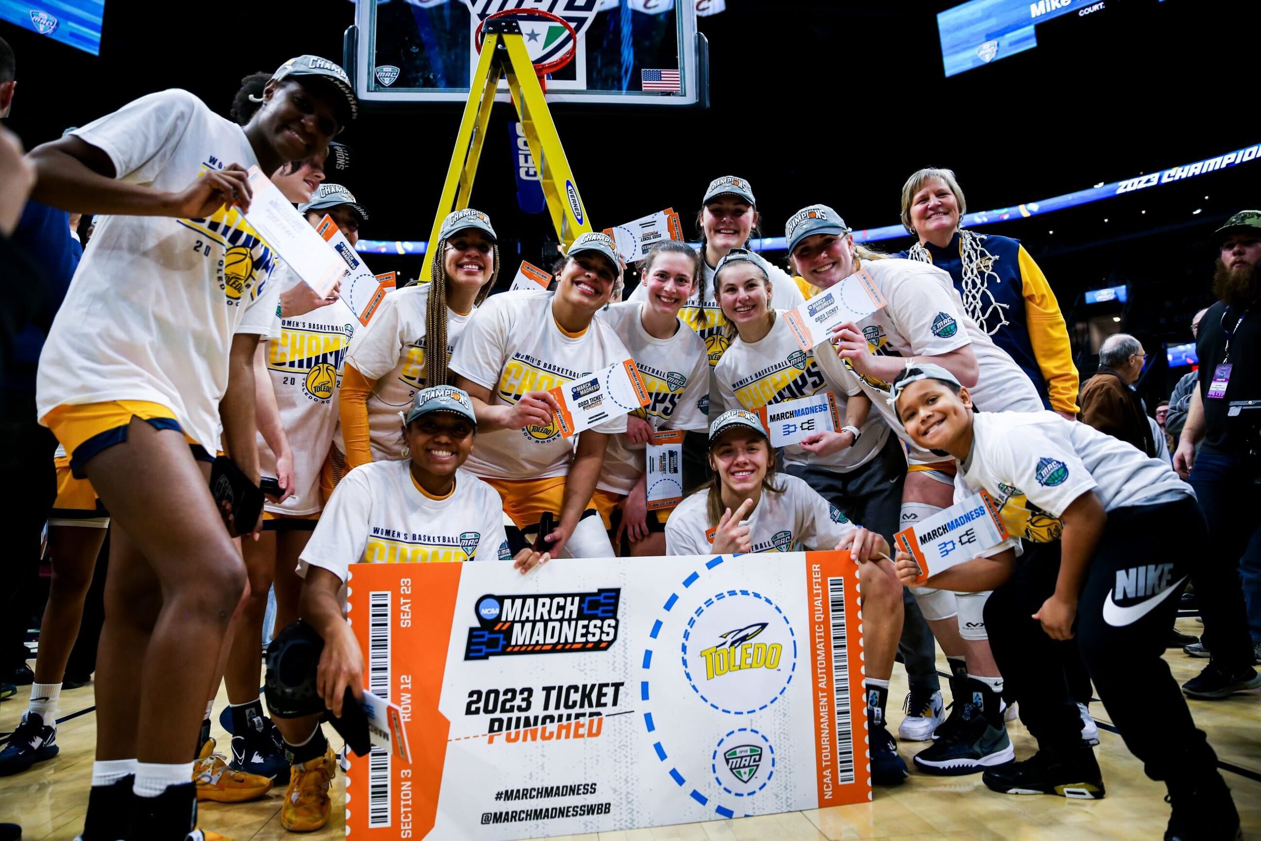 Women's Basketball Players celebrate winning the MAC tournament with a Ticket Punched sign