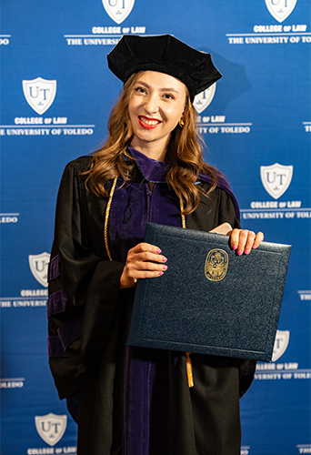 UToledo College of Law graduate Alona Matchenko posed in her cap and gown while holding her diploma.