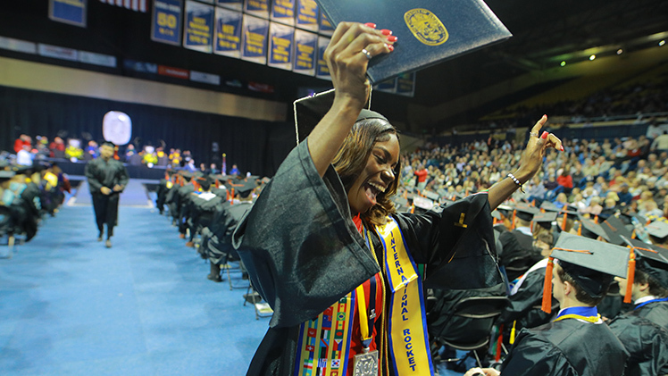 A UToledo female graduate celebrates after receiving her diploma.
