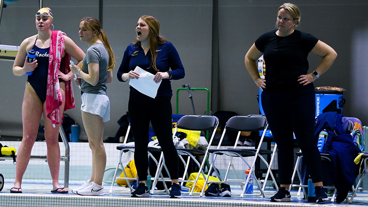 Photo of Hannah Beavers, a senior on the University of Toledo women's swimming and diving team, who is now a student coach on the team, along with swimmers during a match..