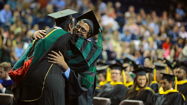 Dr. Shirley Bodi, an assistant professor in the Department of Family Medicine, hugs Dr. Anil Mishra after his hooding during Friday’s College of Medicine Commencement in Savage Arena.