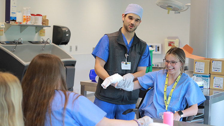 Dr. Kyle Scarano, an orthopaedics resident at The University of Toledo College of Medicine and Life Sciences, applies a short arm cast to Milla Nye, a freshman this fall at New Riegel High School, at CampMed.