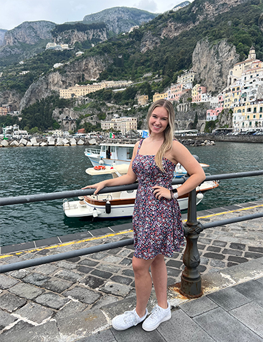 Jordyn Fearon, a law and social thought sophomore at UToledo, poses in front of boats in the ocean and homes on a cliff in Sorrento, Italy.