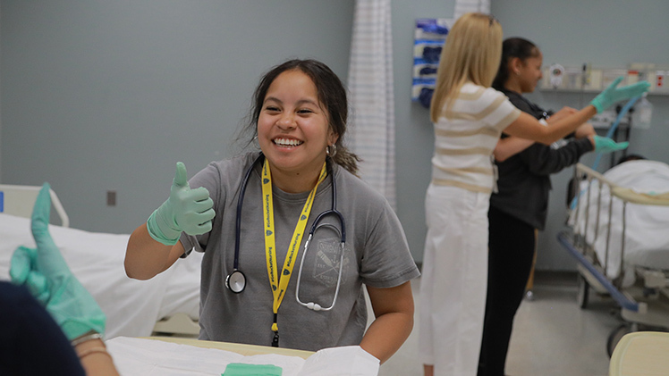 Gianna Anderson, a student at Walsh Jesuit high school, gives a thumbs-up after learning how to properly don sterile gloves during the June session of Rocket Nursing Camp.