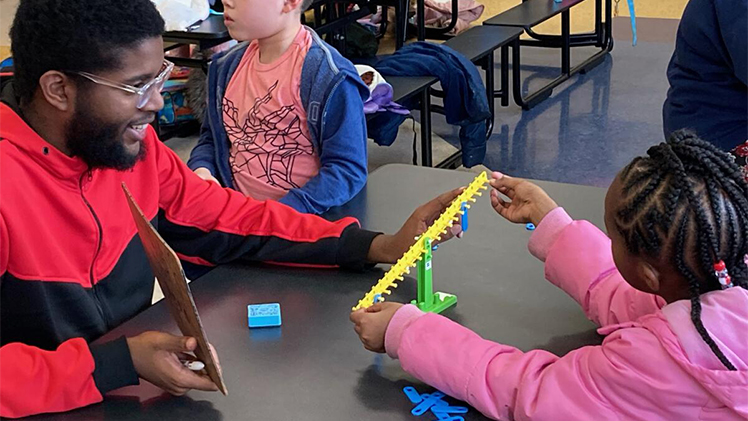 UToledo student William Quinones Ramos, who is pursuing a degree in math education, teaches the concept of “equals” meaning “the same as” to Escuela third graders in after-school math tutoring.