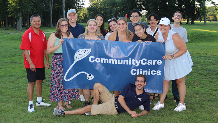 University of Toledo College of Medicine and Life Sciences students who help run The ComunityCare free medical clinic pose outside with a CommunityCares Clinic sign.