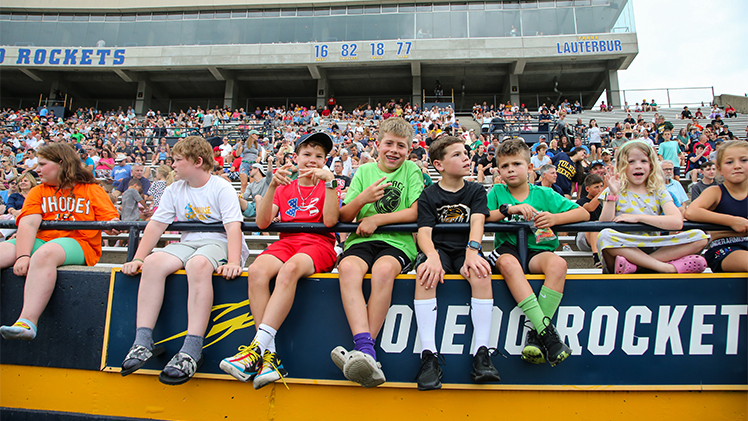 A photo of children sitting at the railing of the Glass Bowl during the Italian Bowl at UToledo's Glass Bowl.