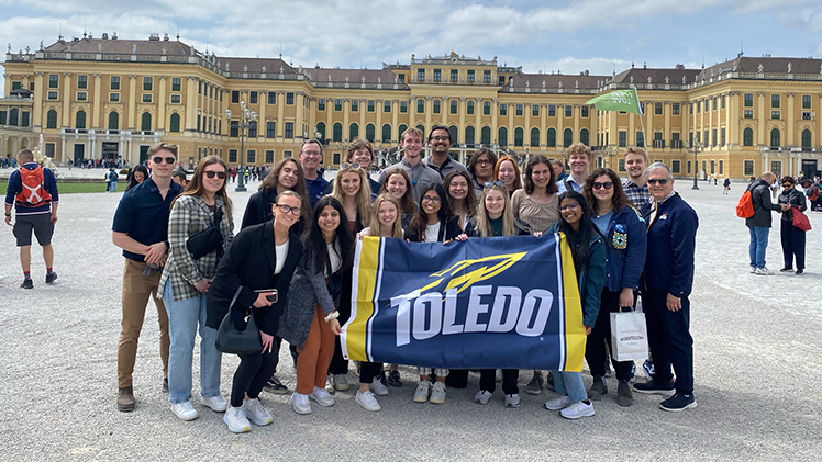 UToledo engineering students in the Roy and Marcia Armes Engineering Leadership Institute (ELI) and Dean of the College of Engineering, Dr. Mike Toole, and others pose with a UToledo flag with Vienna's famed Schönbrunn Palace in the background.
