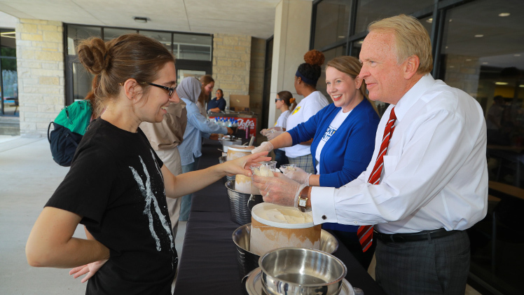 UToledo President Gregory Postel hands a cup of ice cream to Rebecca Brown, a senior in computer science engineering technology, as Sara Clark, assistant dean of student experience and belonging, looks on during Sundae on a Monday outside of Thompson Student Union. The annual event is part of the Welcome Weeks activities that kick off fall semester for new and returning Rockets.