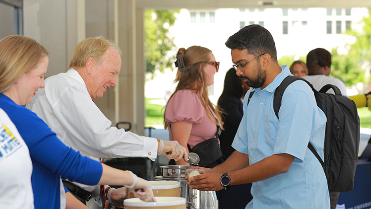 Abrar Hossain, a freshman studying computer science, begins his sundae assembly with a dollop of ice cream from Postel during Monday’s Welcome Weeks event.