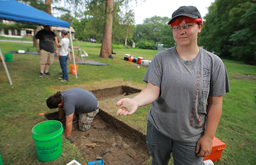 Senior Go Holsinger, who was on their first excavation, holds a projectile point they found  at the main excavation site.