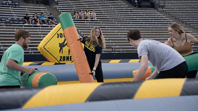 Students try to best each other during a game of inflatable jousting in the Campus Activities and Programming Carnival in Glass Bowl Stadium Friday evening following New Student Convocation. 