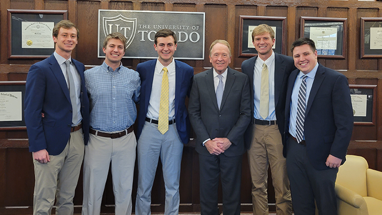 UToledo finance student Kevin Bishop poses with two of his brothers and one of his cousins, all of whom are also Rockets along with President Gregory Postel.
