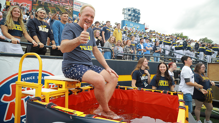 UToledo President Gregory Postel gives the thumbs up in the dunking booth shortly before being dunked in Saturday’s home opener.