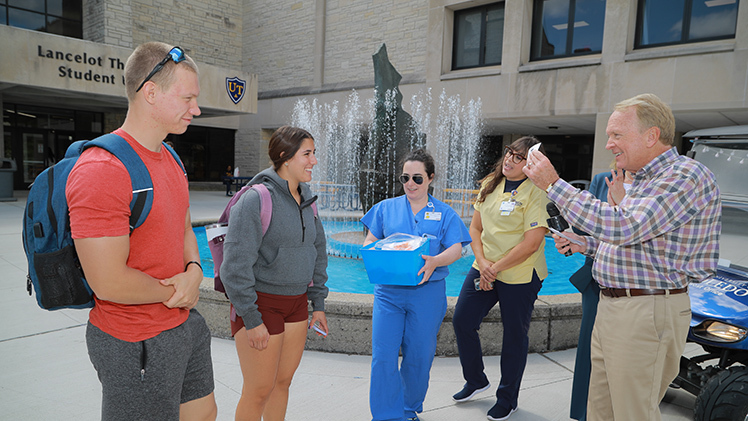 Jacob Mueller, a freshman studying finance, and Sophia Mckarus, a freshman studying early childhood education, answer UTMedCenter Trauma Department’s trauma medicine trivia questions from UToledo President Gregory Postel during a Candy Cab stop Monday in front of Thompson Student Union.