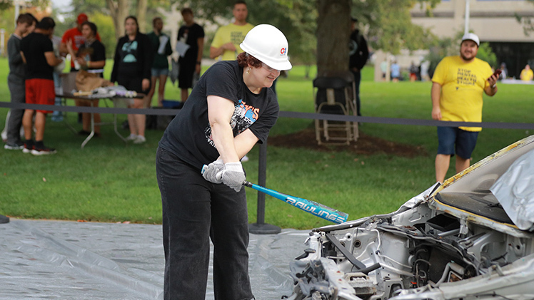 Ellen Papadis, a freshman studying sociology, takes a swing at a junked car during Thursday’s Light Up the Night event in Centennial Mall. Light Up the Night was one of three Main Campus events to promote physical, mental and overall well-being as part of a Day of Wellness.