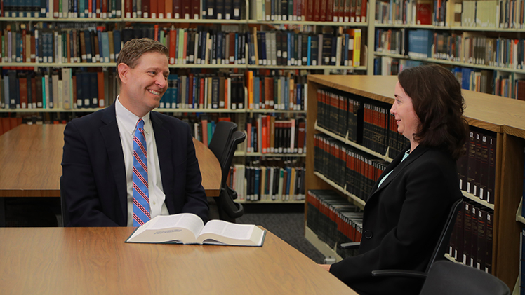 Lee Strang, the John W. Stoepler Professor of Law and Values in the UToledo College of Law and the new center’s director, talks with a female law student in the law library..