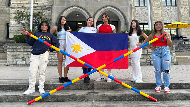 A photo of UToledo students in the Filipino American Association holding up the Philippines National Flag in a posed group photo.