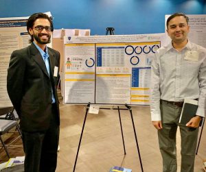 Dr. Pranav Patel and Dr. Varun Vaidya stand next to a poster at a reserach conference.