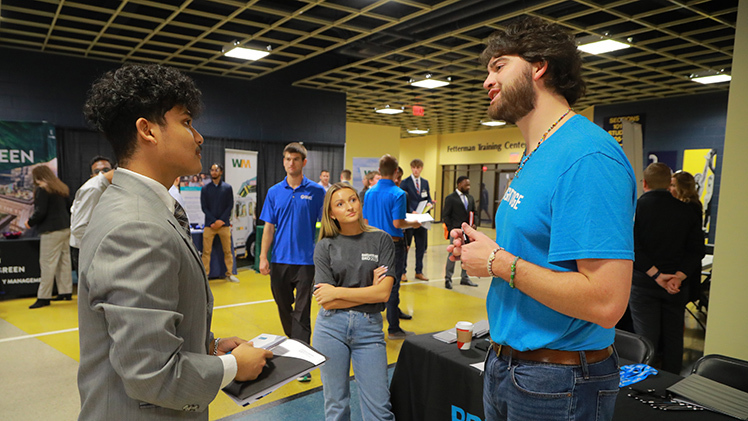 Mayukh Shrestha, a junior studying information systems, speaks to representatives from BrightEdge Technologies on Thursday at the John B. and Lillian E. Neff College of Business and Innovation’s Fall 2023 Job Fair in Savage Arena.