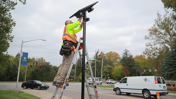 John Maletic Jr. installs a license plate-reading camera on the west side of Main Campus.
