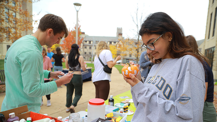 Rafel Alshakergi, a freshman studying political science, decorates a small pumpkin during the Thursday's Honors Fall Fest on the Honors Academic Village courtyard.