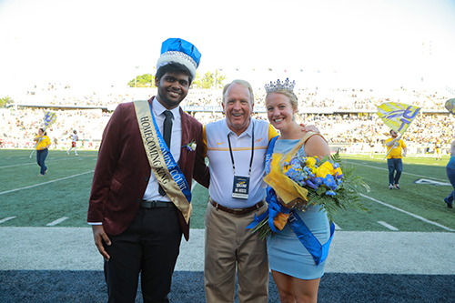 2023 Homecoming King Dhiraj Mohite and Homecoming Queen Ella Moscinski pose with UToledo President Gregory Postel during Saturday’s football game. 