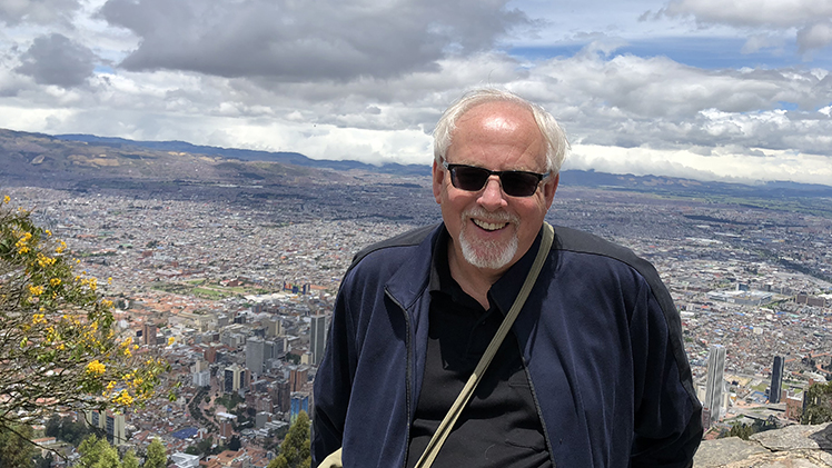 Photo of Dr. Dale Snauwaert, a professor in the Department of Educational Studies, outside on a mountain with a view of a city behind him.