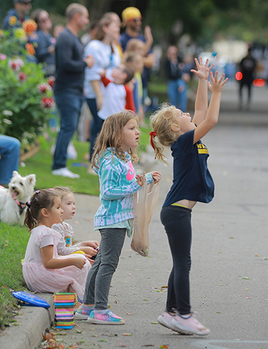 chikldren reach out to grab candy tossed to them as the 2023 UToledo Homecoming Parade rolls by.