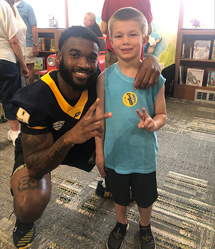 Larry Stephens, a senior wide receiver studying marketing, is a role model for the deaf community. Here he meets with a youngster with a cochlear implant just like his at the Toledo Public Library following a public reading sponsored by the Ability Center of Greater Toledo.