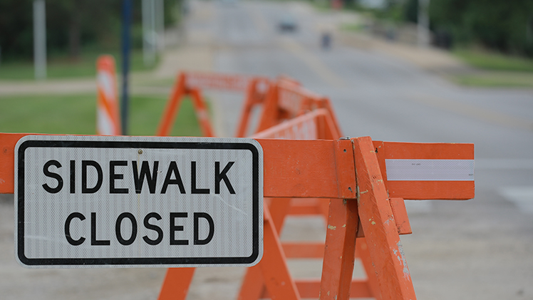 A photo of a construction barricade with a sign that says "sidewalk closed."