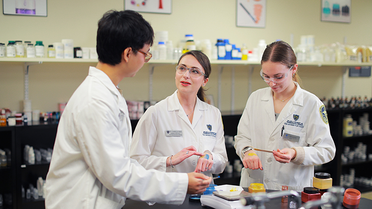 Dr. Gabriella Baki, center, an associate professor of pharmaceutics, works in her lab with undergraduate cosmetic science and formulation design students Lin Khant Maung, left, and Lois Lancaster.