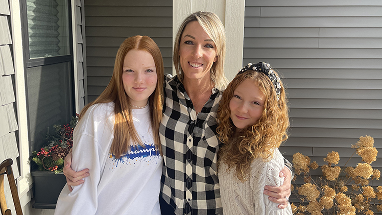 UToledo Law graduate Kayte Geist' poses with her two young daughters outside her home.