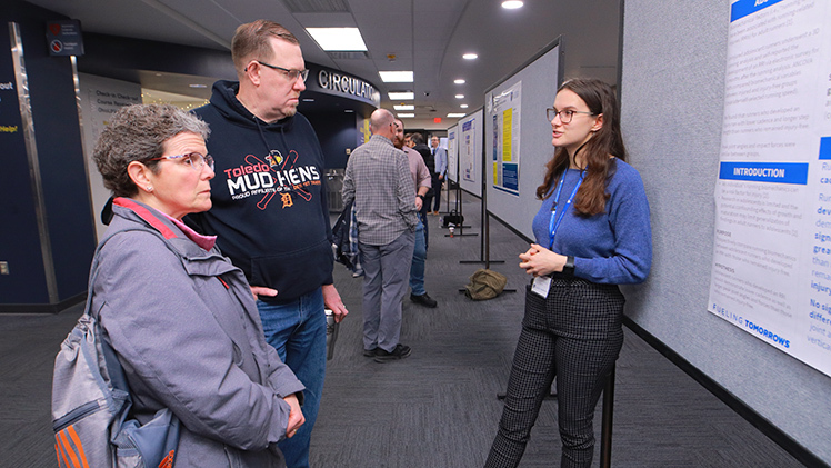 Eryn Close, a senior majoring in exercise science, explains her poster to her parents, Gaylyn and Michael, Friday during the 2023 Undergraduate Research Exhibition.