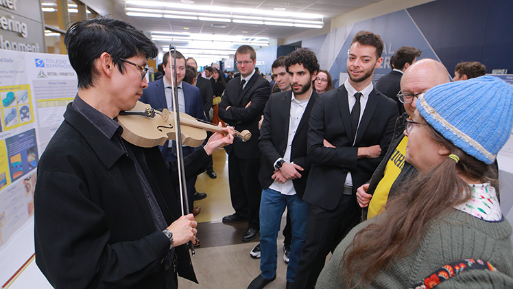 Merwin Siu, artistic administrator of The Toledo Symphony, plays a 3D-printed violin created by an engineering student team during the UToledo Engineering Senior Design Expo.