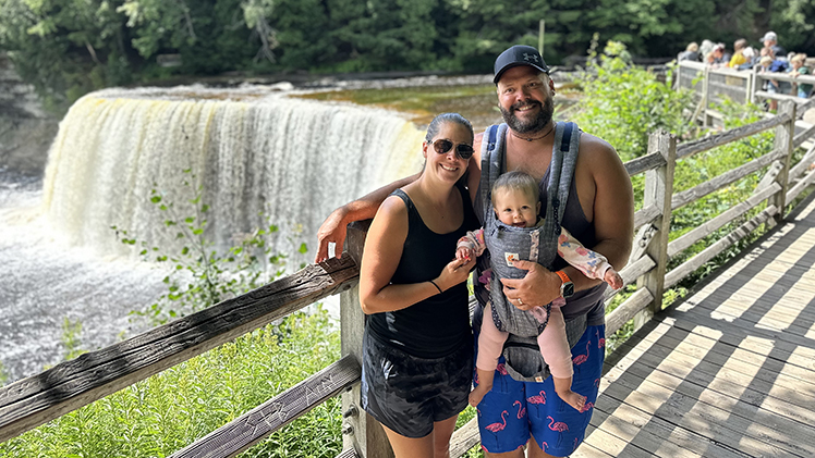 Bill Maloy and his wife, Paige Maloy, and their daughter, Addison, on a hiking trip with a small waterfall behind them.