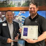 Jason Toth, senior associate vice president for facilities and construction at UToledo, left, receives the Excellence in Energy Award for Energy Efficiency from Jonathan Anderson, director of strategic accounts and customer care at NRG Energy, on Wednesday, Nov. 29.
