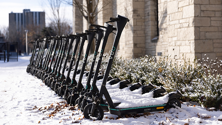 Photo of a lineup of Veo electric scooters in the snow on the UToledo campus.